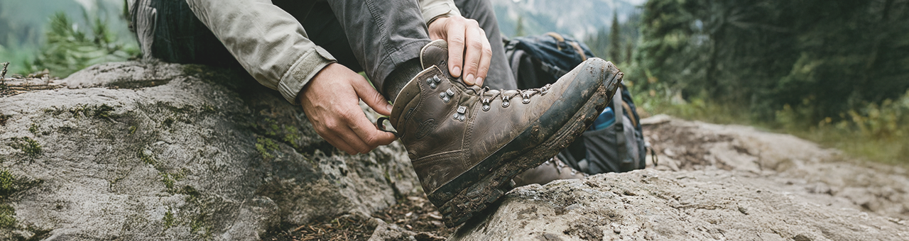 Randonneur sur un sentier de montagne portant des chaussettes de randonnée Wrightsock anti-ampoules.